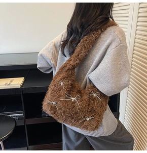 Detail of brown plush shoulder bag with decorative silver heart pendants and ribbon bows