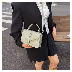 Détail du sac à main matelassé vert clair avec boucle argentée sur fond urbain épuré