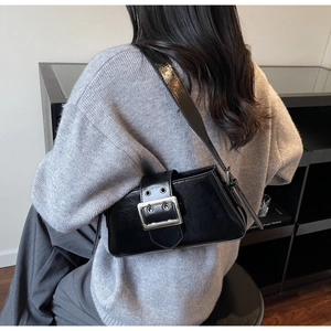 Detail of black glossy leather crossbody bag with adjustable strap and silver square buckle