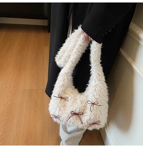 Detail of white plush shoulder bag with red ribbon bows and small gold bells texture