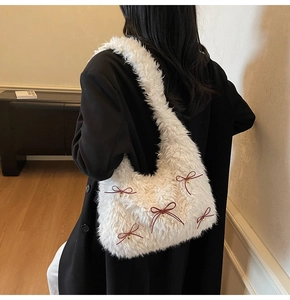 Close-up of white plush shoulder bag with red bows on soft faux fur texture
