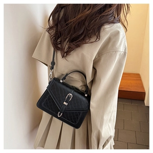 Détail du sac à bandoulière noir tissé avec boucle métallique et fine sangle sur modèle