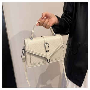 Détail du sac crème avec rabat à texture tissée et boucle argentée élégante