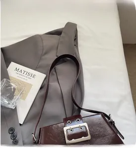 Detail of deep brown leather crossbody bag with metallic silver square buckle