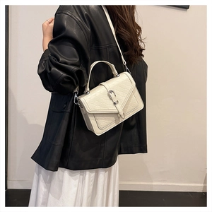 Détail du sac bandoulière crème avec texture en losange et boucle argentée sur modèle