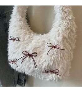 Close-up of white plush shoulder bag featuring red bows and golden heart charms