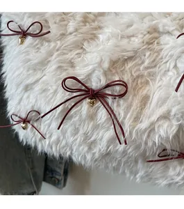 Close-up of white plush fabric with dark red bows and golden heart-shaped metal pendants