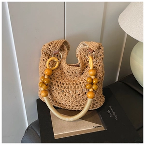 Detail of hand-woven hollow knit bag featuring decorative wood bead handle and retro texture