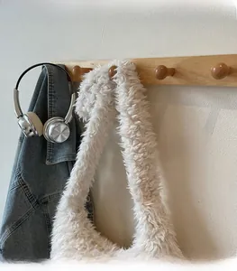 Detail of soft white plush shoulder bag with wide strap on a wooden clothes hanger