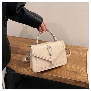 Détail du sac tressé crème avec boucle argentée et bandoulière réglable