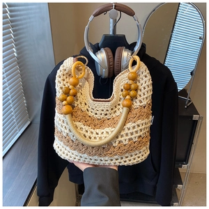 Detail of bohemian woven handbag featuring bicolor wave pattern and natural wood bead handle