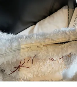 Detailed macro view of smooth white plush handbag zipper with a golden heart charm