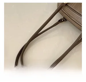 Détail de la poignée en cuir ronde et finitions dorées sur un sac à main tissé marron