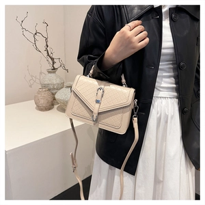 Détail du sac à main matelassé beige avec boucle en métal argenté et texture tissée fine