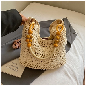 Detail of beige crochet tote bag with 3D floral patterns and decorative wooden bead handle