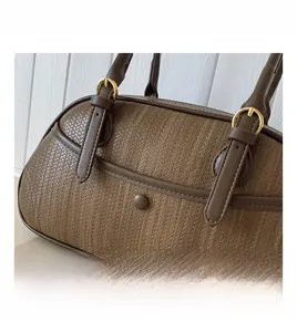 Détail de la texture tressée marron et boucle dorée d'un sac à main élégant pour femme