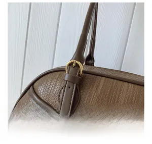 Détail macro du sac tressé marron avec boucle dorée et bandoulière réglable
