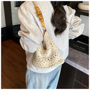 Detail of crochet weave pattern on a cream beach bag with natural wooden beads