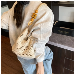 Detail of hand-woven beige crochet shoulder bag with large wooden beads on strap