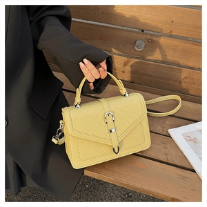 Détail du sac tissé jaune crème avec fermoir métallique et poignée en gros plan précis