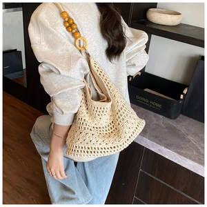 Detail of hollow woven shoulder bag featuring large wooden beads and beige knit texture