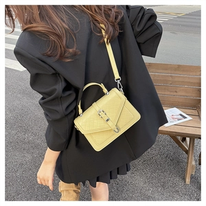 Détail du sac matelassé jaune clair avec boucle argentée et poignée en décor urbain