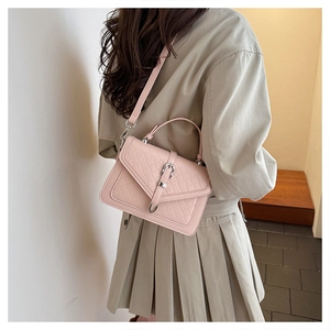 Détail d'un sac à main matelassé rose clair avec serrure métallique et bandoulière réglable