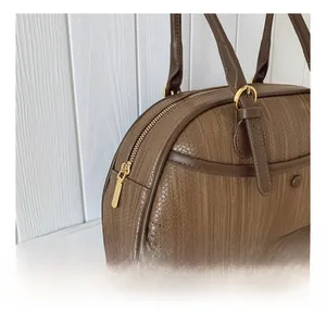 Détail de la fermeture éclair dorée et de la texture tissée du sac vintage marron