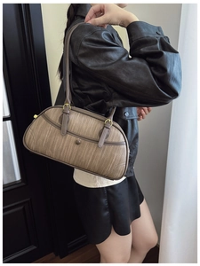 Detail of a brown woven texture bowling bag with leather straps and gold buckle accents