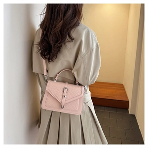 Sac à main rose matelassé avec boucle en métal porté avec un trench-coat beige classique