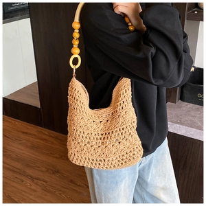 Detail of the woven beach bag featuring a unique wooden bead handle and floral hollow pattern