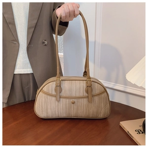 Detail of a beige woven cylindrical shoulder bag featuring fine straps and metal buckles