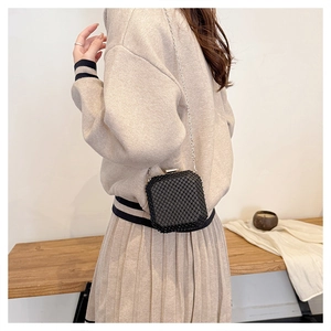 Dettaglio mini borsa nera con paillettes, tracolla a catena d'argento e chiusura clip