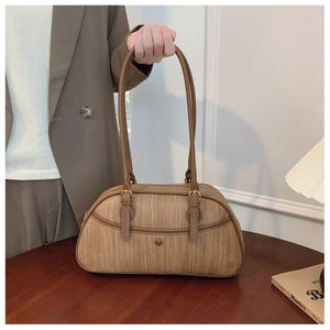 Detailed view of the brown textured leather surface and sturdy handle of the Boston bag