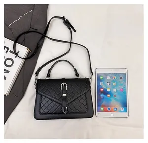 Détail du sac à main noir tressé avec fermoir argenté à côté d'un iPad pour comparer la taille