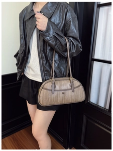 Détail d'un sac à bandoulière Boston marron tissé avec surface texturée et boucle en métal