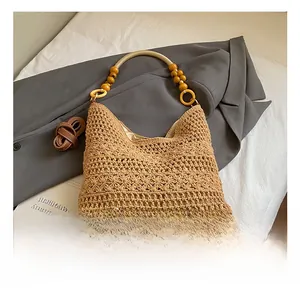 Close-up of beige crochet tote bag with wooden bead strap and leather detail