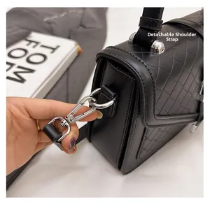 Détail de la bandoulière amovible avec boucle en métal argenté sur un sac à main noir