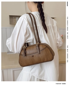 Detail of a brown woven texture shoulder bag with leather trim and gold metal hardware