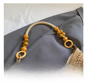 Detail of hollow woven handbag featuring wooden beads handle and yellow ring connectors
