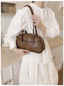 Sac à bandoulière marron à texture tressée porté par un mannequin en cuisine moderne