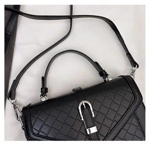 Détail de la texture en cuir tressé noir et boucle argentée sur un sac à bandoulière