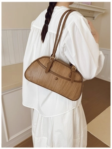 Detail of brown woven texture shoulder bag with premium leather piping and gold buckles