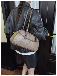 Detail of taupe woven shoulder bag with smooth leather trim and golden zipper on model