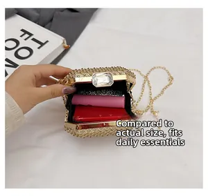 Dettaglio interno di una borsa da sera dorata con strass contenente telefono e rossetto