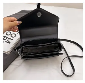 Vue intérieure du sac bandoulière noir avec plusieurs compartiments et boucle magnétique argentée