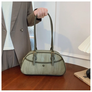 Detail of olive green handbag with vertical woven texture and gold hardware on wood