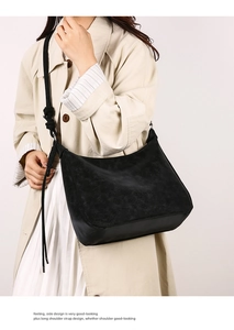 Close-up of matte black crossbody bag with decorative rope knot strap on trench coat