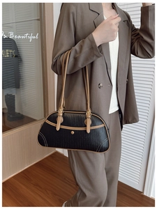 Detail of a retro woven underarm bag with brown leather trim and metallic buckle closure