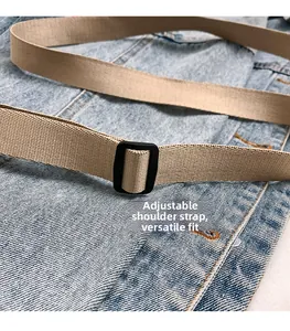 Detail of adjustable khaki woven shoulder strap with black buckle on denim background